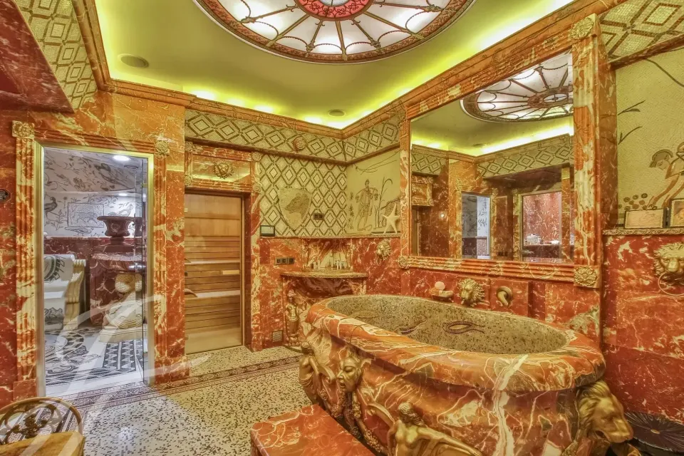 Bagno con vasca in pietra e finiture ornamentate