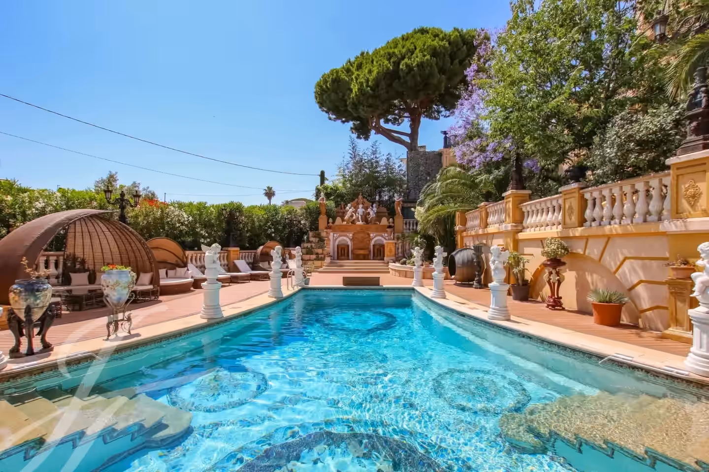 Piscina del castello circondata da terrazza, giardini e alberi.